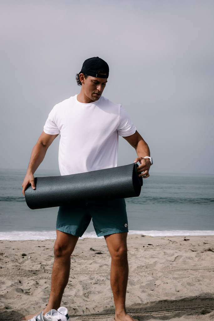 The coach in the beach, folding his workout mat.